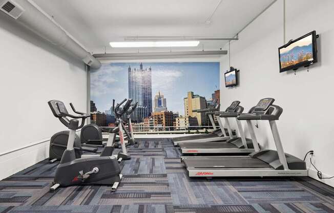A gym with treadmills and a city view on the wall.