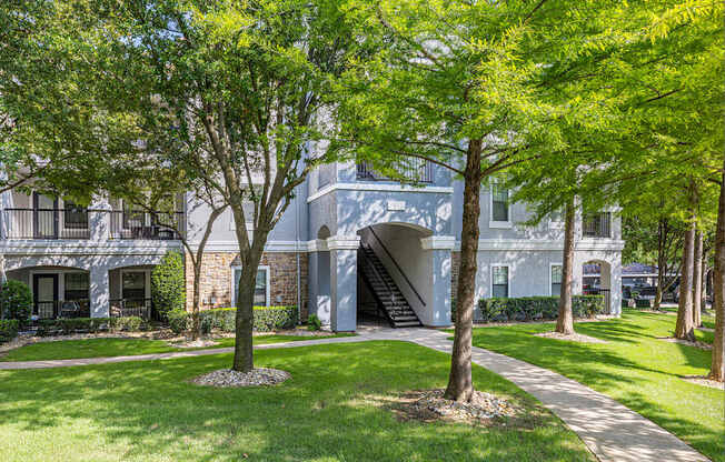 A tree in front of a building with a staircase.