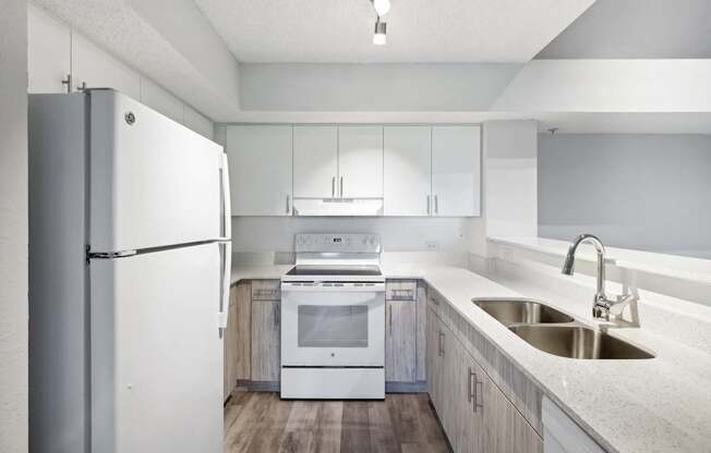 A modern kitchen with a white refrigerator, stove, and sink.