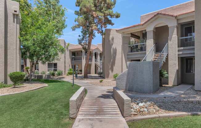 A concrete walkway leads to a building with a balcony.