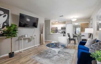 A modern living room with a blue sofa and a flat screen TV mounted on the wall.