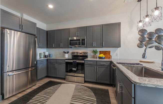 A modern kitchen with a stainless steel refrigerator and a black and white striped rug on the floor.