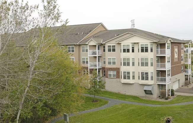 a large apartment building with balconies and a grassy area in front of it