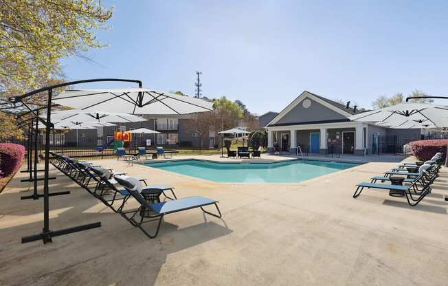 A pool area with sun loungers and a building in the background.
