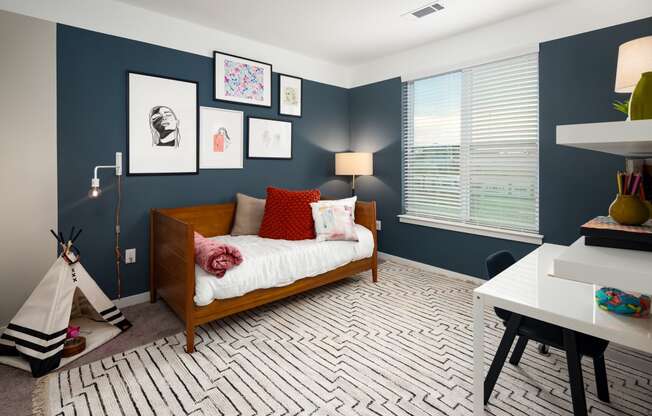 a bedroom with navy blue walls and a white bedspread with red pillows at Abberly Noda Vista Apartment Homes, North Carolina