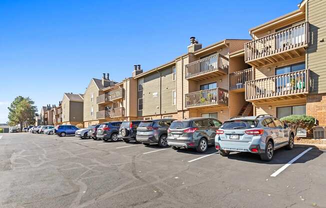 A parking lot with cars and apartment buildings in the background.