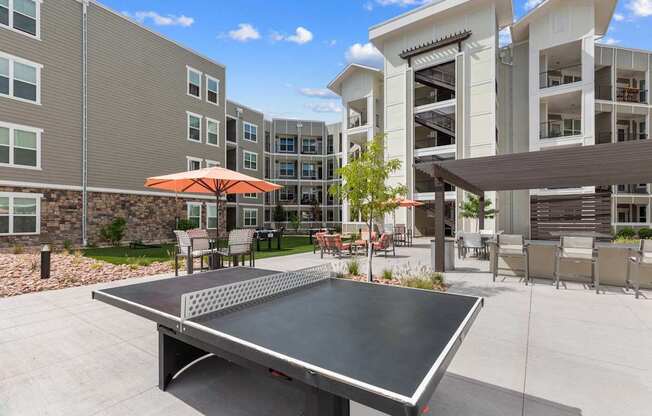 A table tennis table is in the middle of a courtyard with a building in the background.