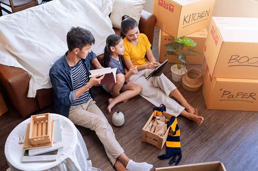 A family is sitting on the floor surrounded by moving boxes.