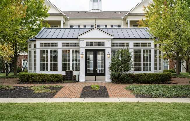 the front of a white house with a black door