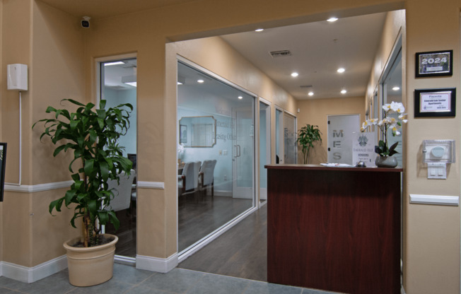 A reception area with a wooden desk and a potted plant.,A reception area with a wooden desk and a potted plant.