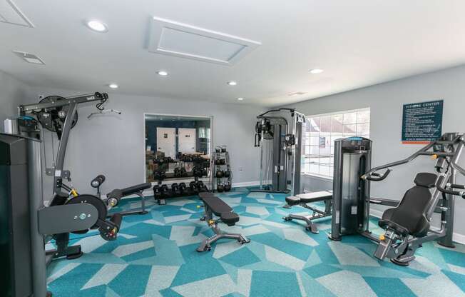 a gym with weights and other exercise equipment in a room with a window