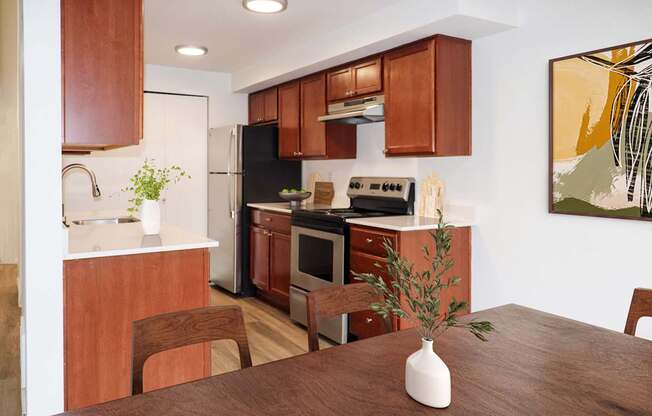 a kitchen with stainless steel appliances and brown wooden cabinets at Heritage Grove Apartments in Renton, WA