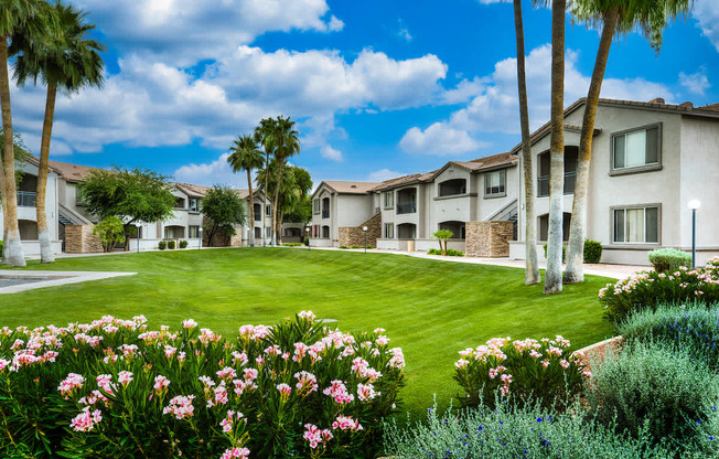 A sunny day at a residential complex with a well-maintained lawn and flowering plants.