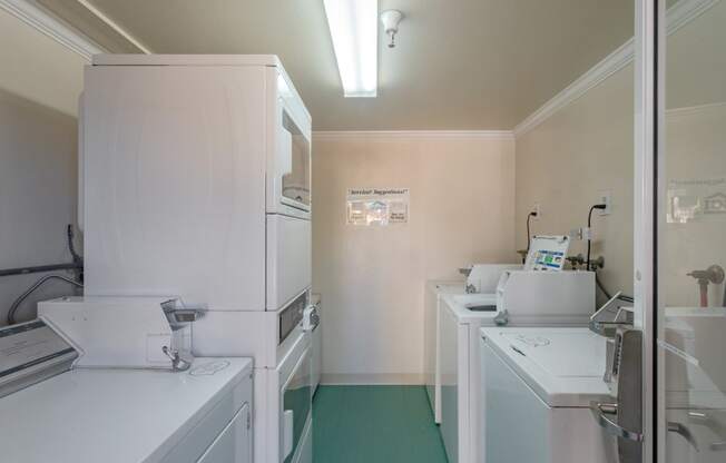 a laundry room with white appliances and a green floor