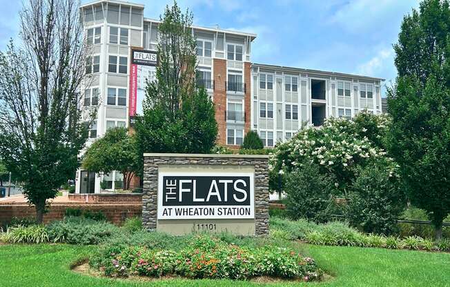 The Flats at Wheaton Station is a white building with a sign in front of it.