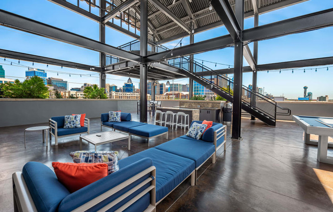 a lounge area with blue couches and chairs and a ping pong table with a view