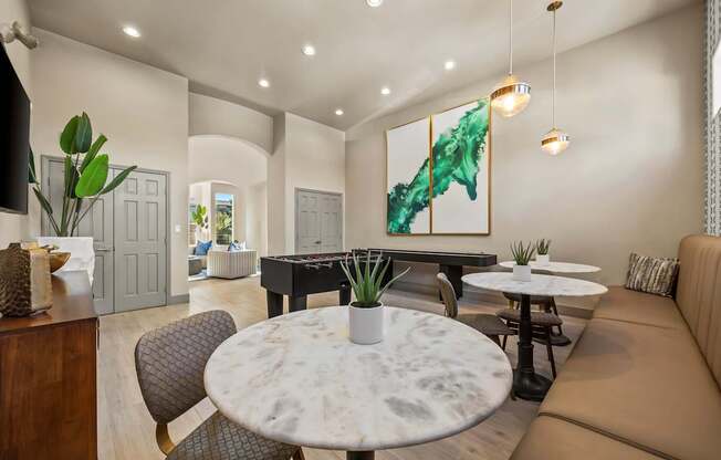 A modern living room with a large painting, a round marble table, and a brown leather sofa.