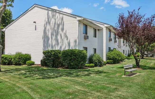 Exterior view of apartment building with green grass and bench seating