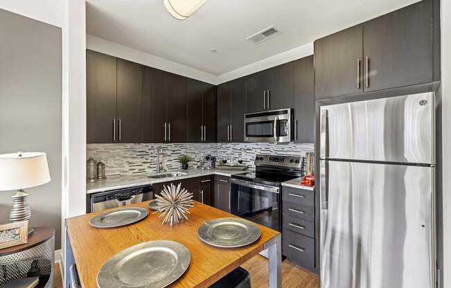 A modern kitchen with a wooden table and grey cabinets.
