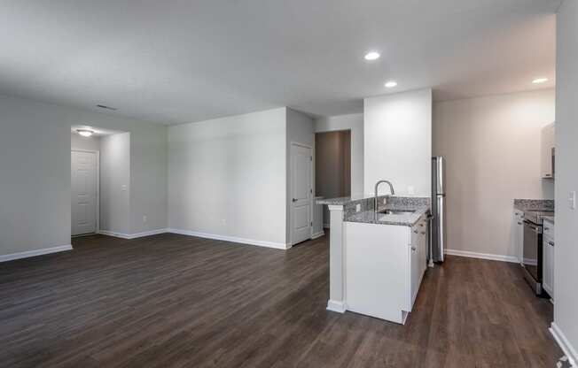 an empty kitchen and living room with white walls and wood flooring