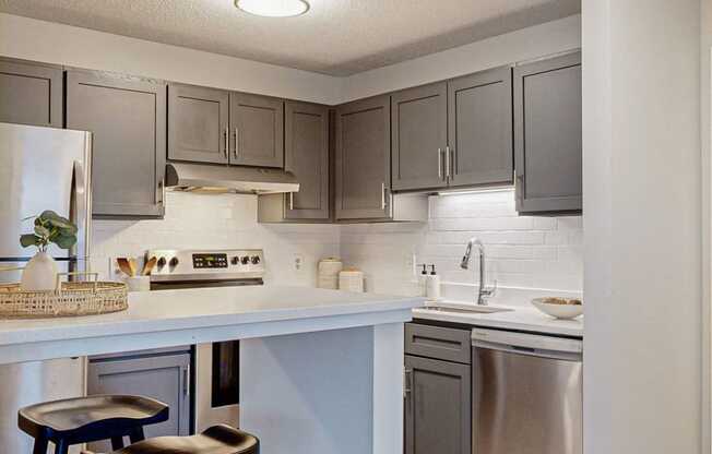 a kitchen with grey cabinets, white countertops and bar stools