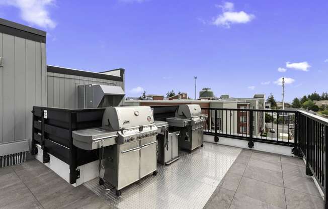 Resident Lounge Area with two barbecue grills and a blue sky in the background at Arabella Apartment Homes, Shoreline, WA