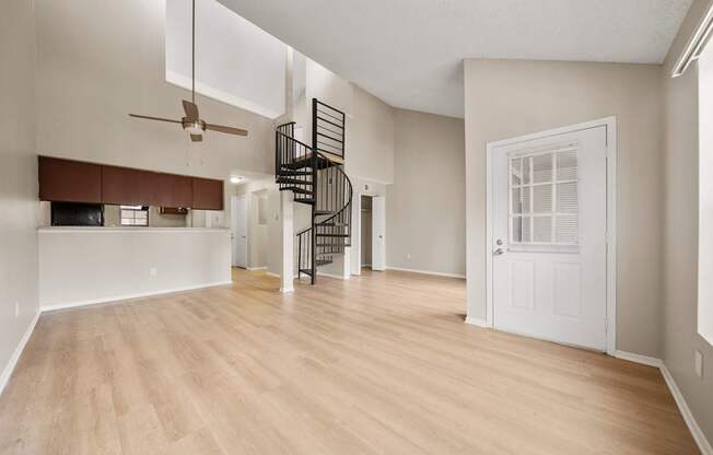 A room with a spiral staircase and a ceiling fan.