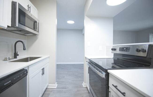 an empty kitchen with white cabinets and stainless steel appliances