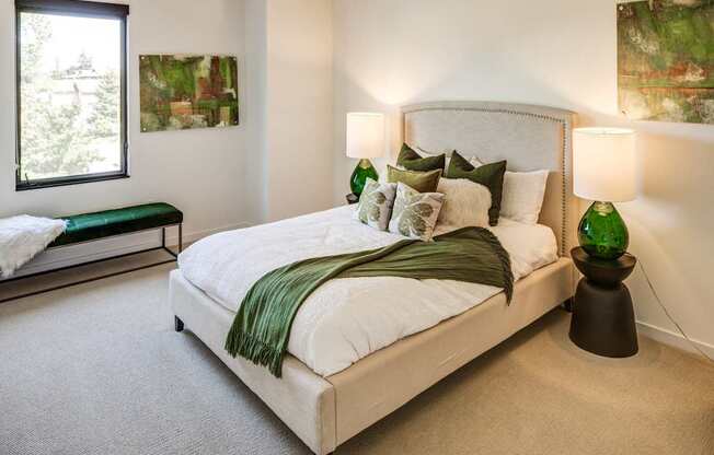 A bedroom with a large bed and two green lamps.