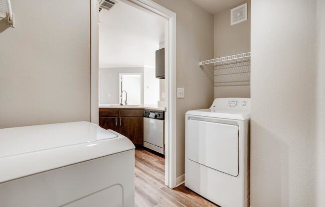 a washer and dryer in a laundry room with a door to a kitchen