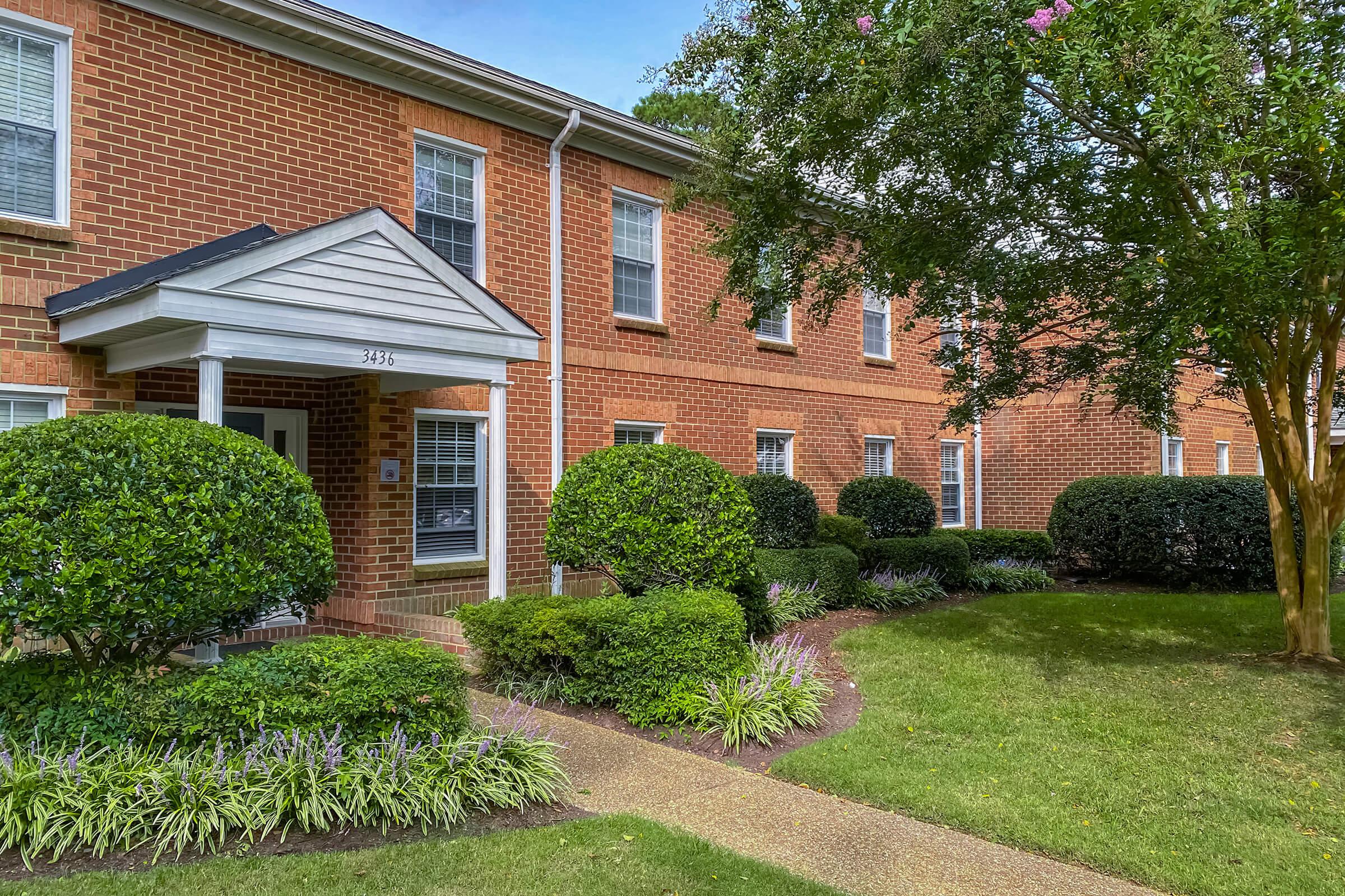 a house with bushes in front of a brick building