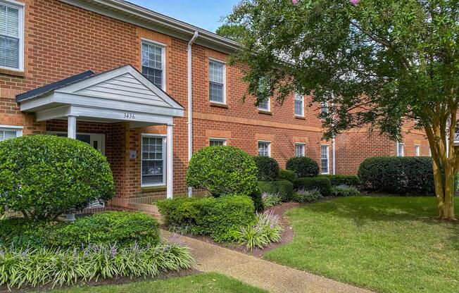 a house with bushes in front of a brick building