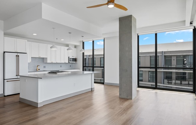a white kitchen with a large island and a large window