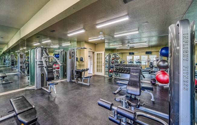 a gym with weights and cardio equipment on the floor and a mirrored wall