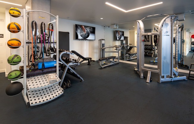 A gym with a variety of equipment including a treadmill, weights, and a bench.