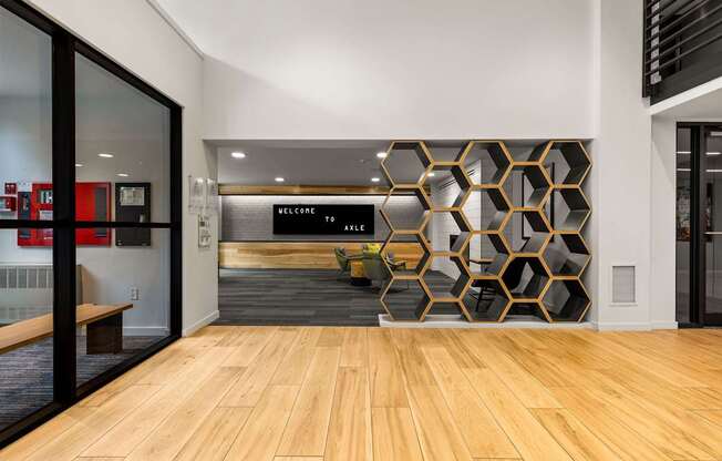 A hallway with a wooden floor and a wall with a hexagonal pattern.