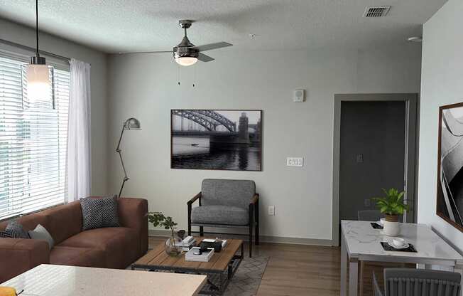 A living room with a brown couch, a coffee table, and a ceiling fan.