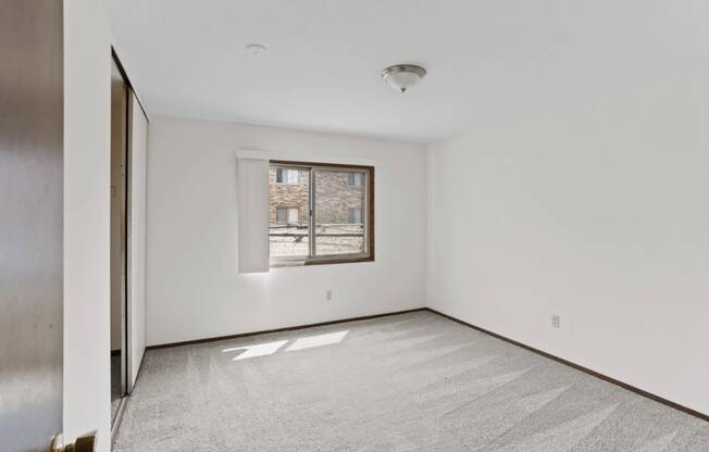 a bedroom with white walls and a window