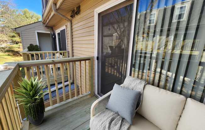 A small balcony with a couch and a potted plant.