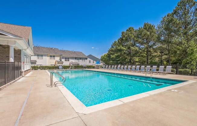 A large outdoor swimming pool surrounded by a concrete patio and lounge chairs.