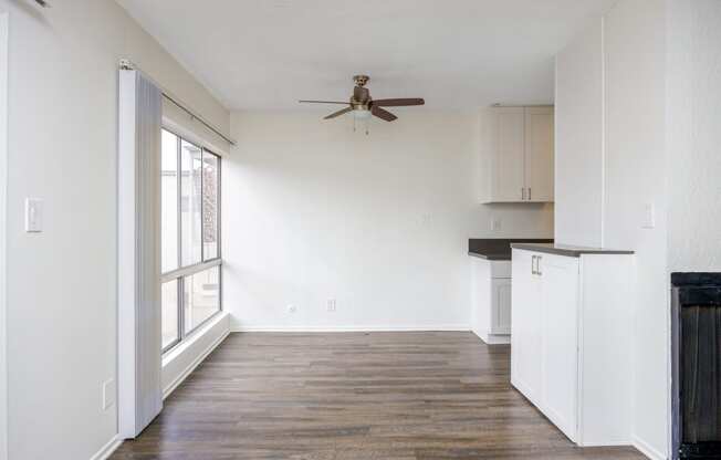 an empty living room with white walls and a ceiling fan