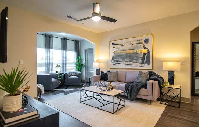 A living room with a grey couch and a painting on the wall.