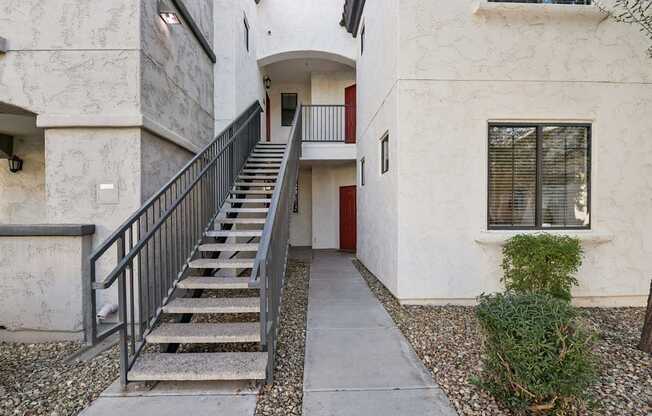 A concrete building with a red door and a staircase leading to the entrance.