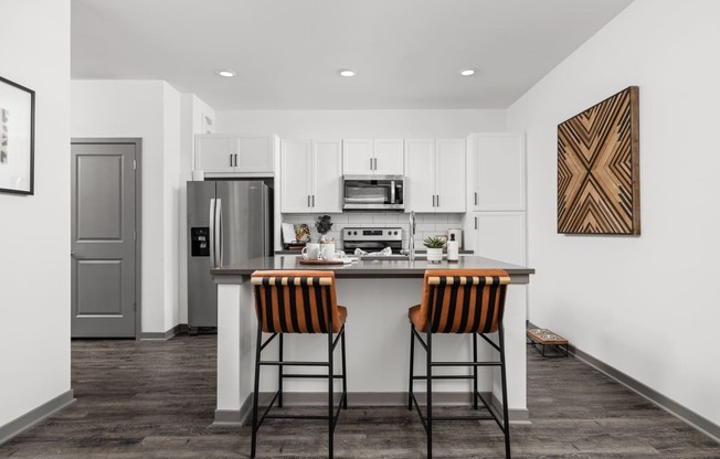 a kitchen with a bar and stools and a stainless steel refrigerator