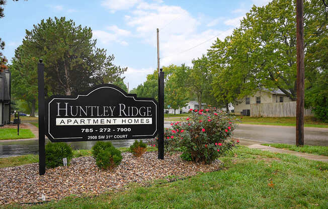 A sign for Hunley Ridge Apartment Homes sits in front of a house.