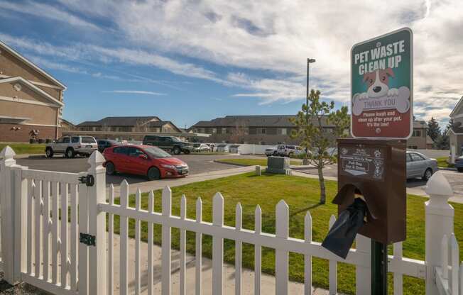 a white picket fence with a sign that says pet waste clean up