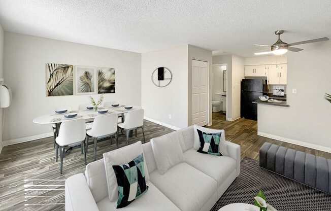 A living room with a white couch and a dining table with chairs.