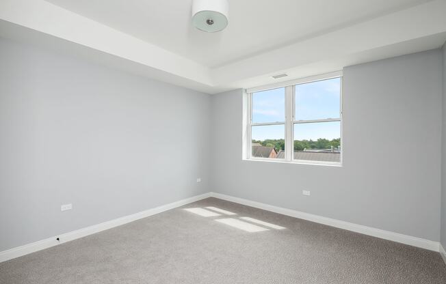 an empty room with a window and carpet