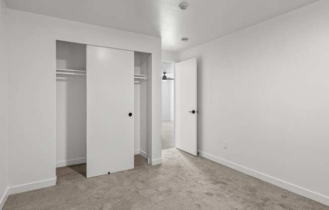 an empty bedroom with white walls and doors to closets