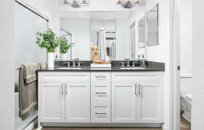 a bathroom with white cabinets and a black countertop at Solstice at Fiddyment Ranch, California